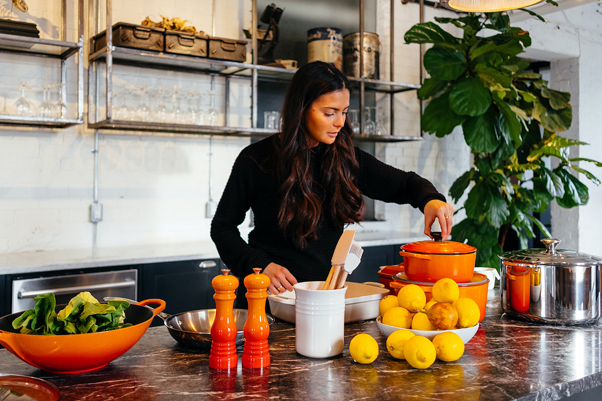 A woman cooking with colorful fruits and vegetables, depicting that Wildtree products are healthy and delicious.